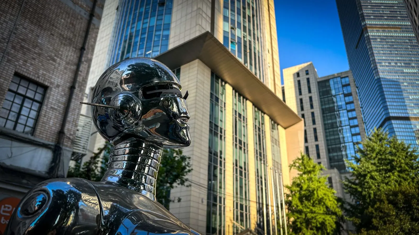 City tech and AI in a modern urban skyline, represented by a robot statue among skyscrapers.