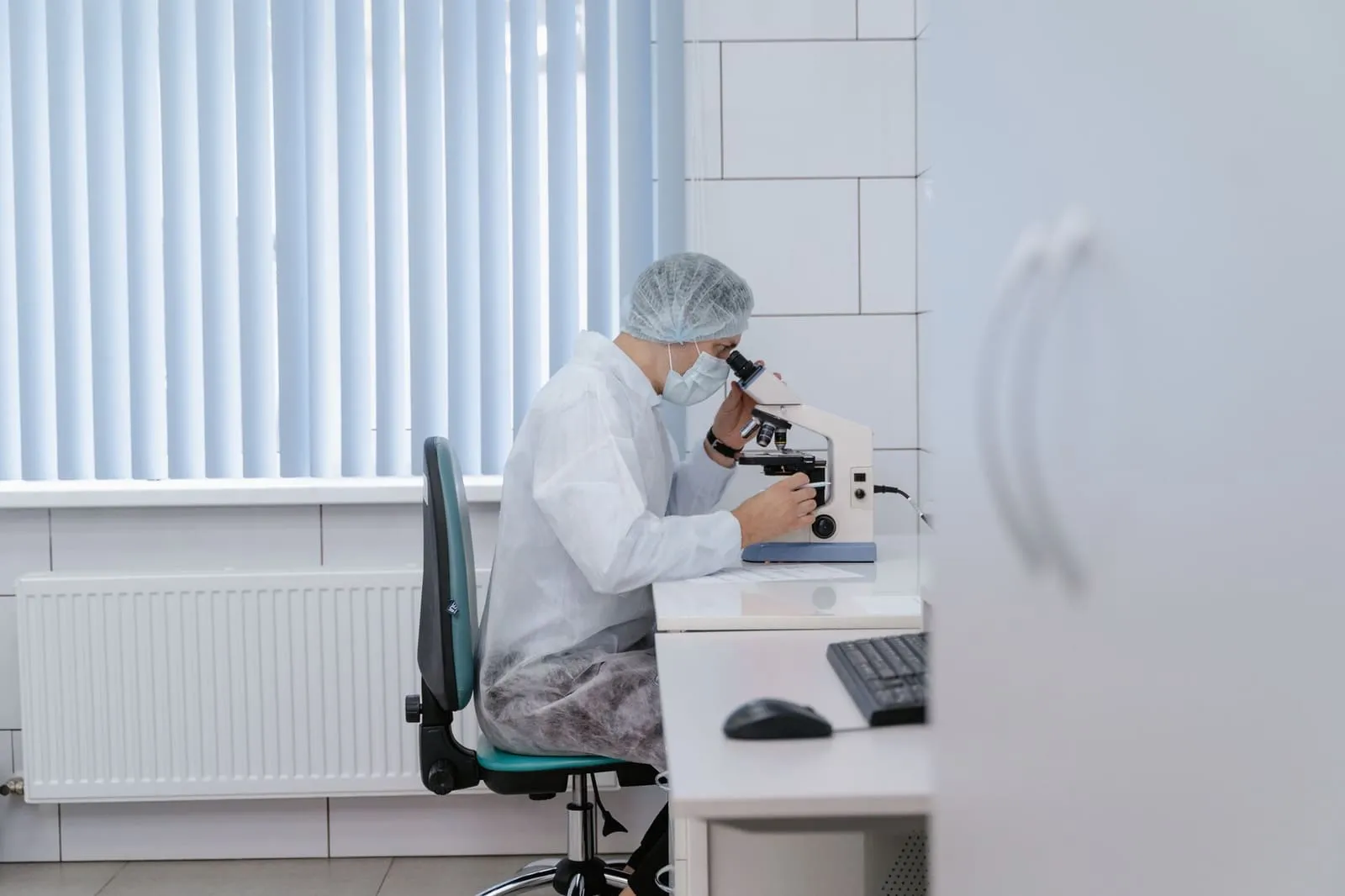 Scientist working in a lab using a microscope for scientific research and analysis.